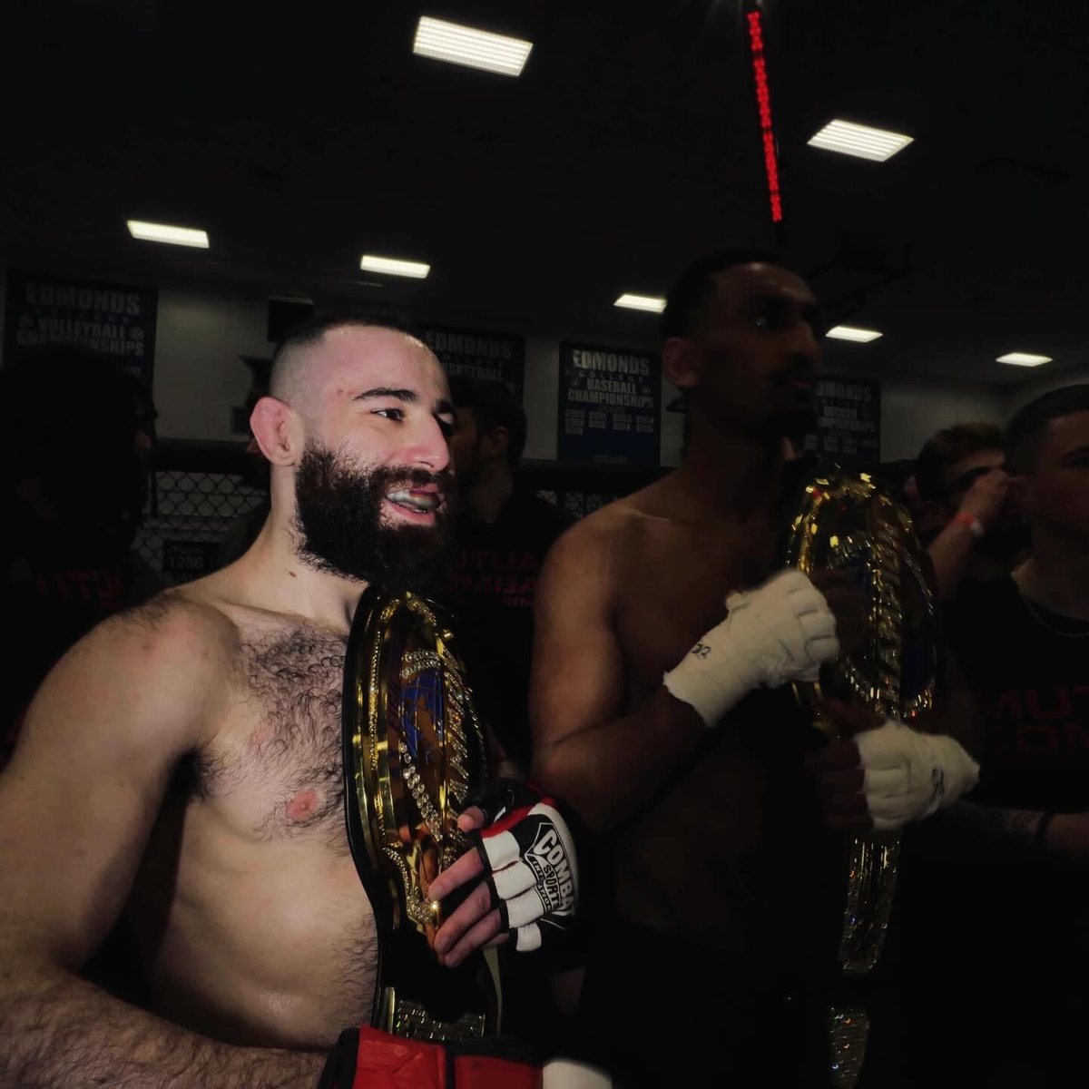 Michael Davtyan holding two championship belts after a win