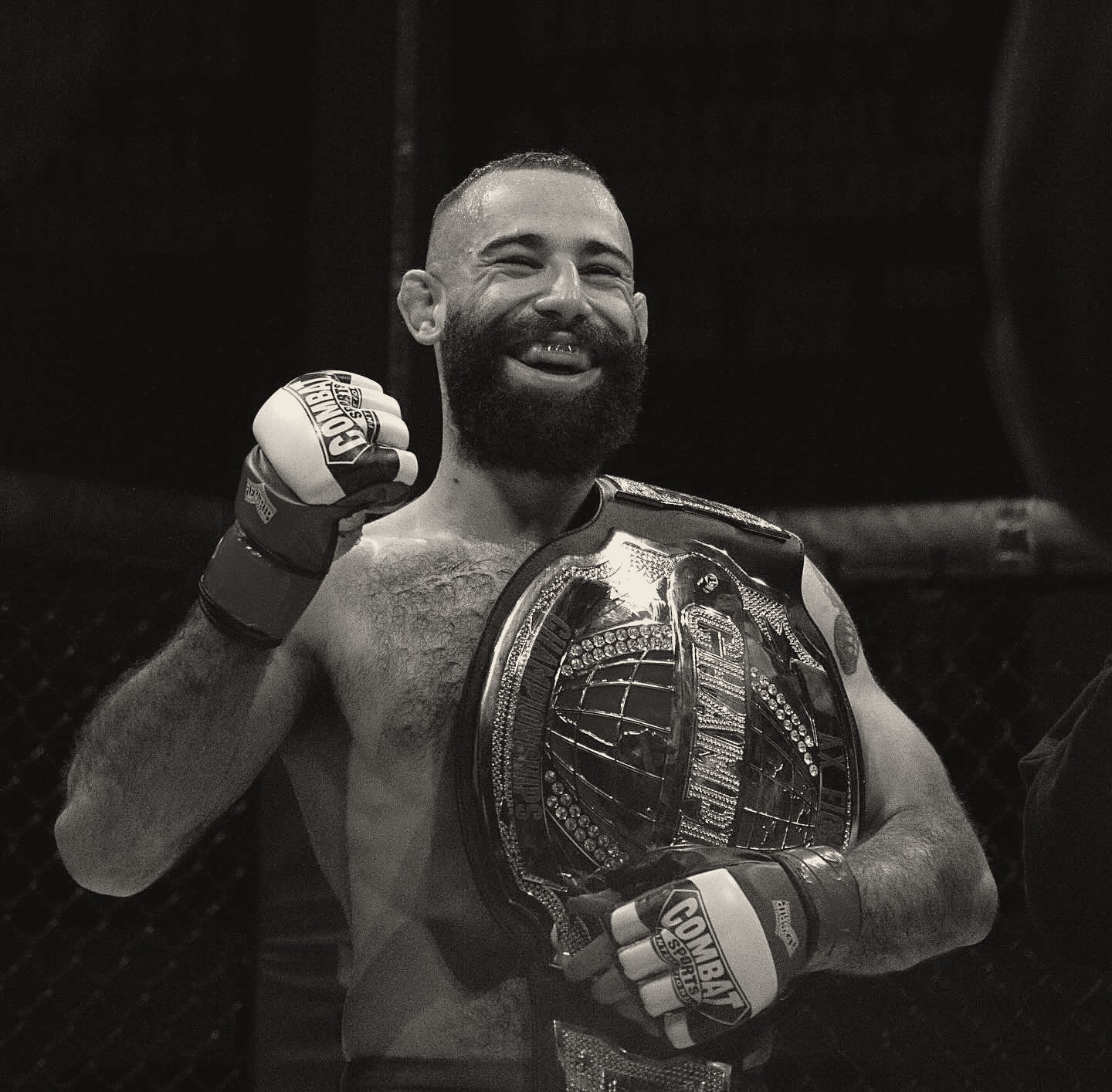 Michael Davtyan smiling in the cage with his championship belt